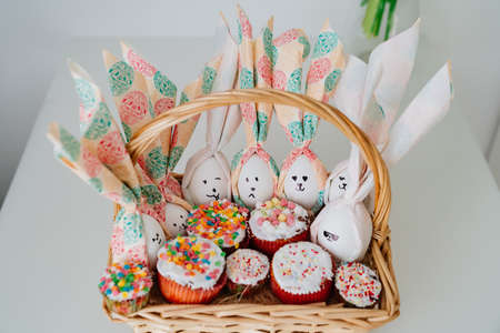 basket with decorated eggs and Easter cakes or muffins.