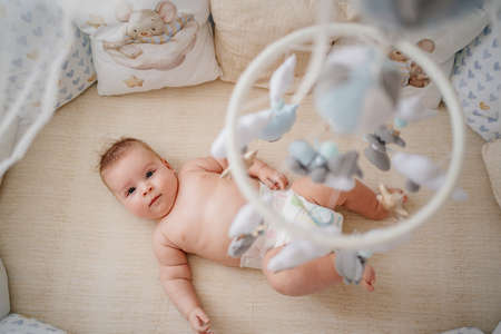 view from above. a baby lies in a white crib with mobile with toys.の写真素材