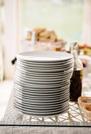 lots of white plates in a stack on the dining room table.の写真素材