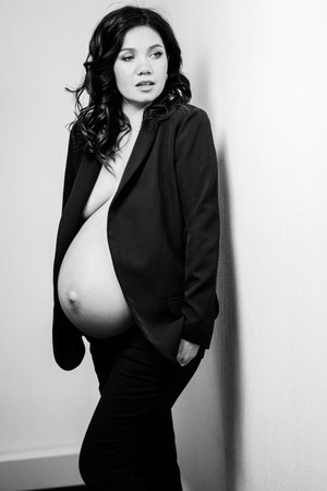 a beautiful pregnant woman in a black jacket with bare breasts and a bellyの写真素材