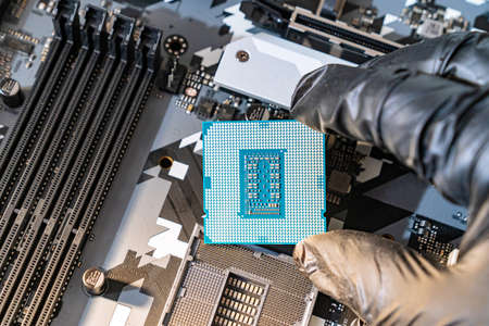 hand of repairman wearing black gloves with a processor. computer workshop.
