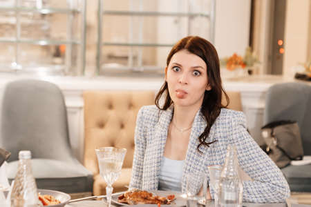 a fun attractive dark-haired woman in a blue jacket at a banquet table.