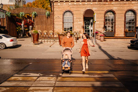 a family with a small child on an autumn walk around the city with stroller.の写真素材