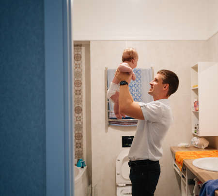 dad plays with newborn son and tosses him up in the bathroom. water proceduresの写真素材