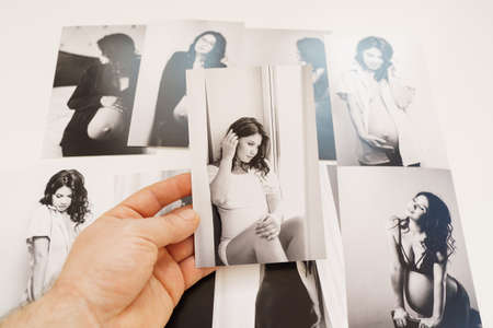 Mens hands hold pictures of a beautiful pregnant woman.の写真素材