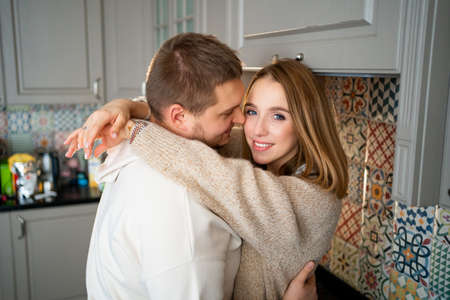 a happy and loving couple fooling around and hugging at home in the kitchen