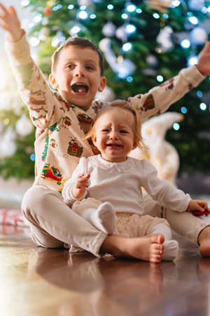 funny toddlers brother and sister at the Christmas tree. holiday for children.