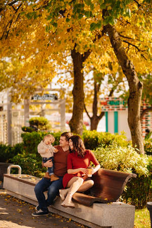 beautiful and happy family on the bench of the autumn embankment.の写真素材