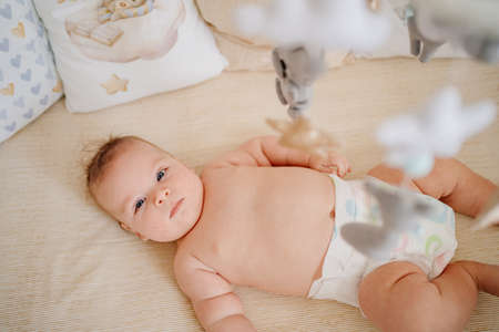 view from above. a baby lies in a white crib with mobile with toys.の写真素材
