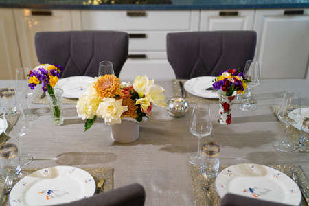served dining table with utensils and flowers in the dining room.
