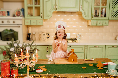 a cute little girl decorates a ginger house with icing.の写真素材