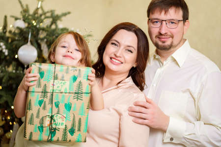 happy family with box of gift by Christmas tree. tradition giving giftsの写真素材