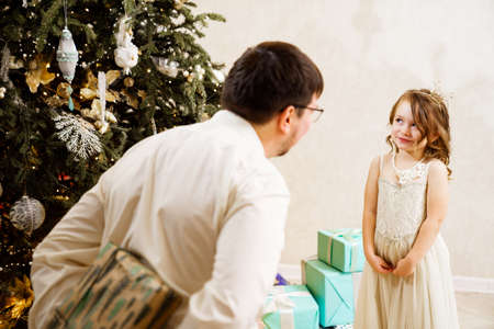 Dad hides behind his back a box with a gift for the baby daughter.の写真素材