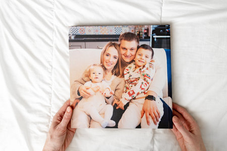 a hands with a book with photos of big family at home on a white background.の写真素材