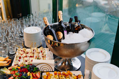 the champagne is cooled in a bucket of ice. serving of alcoholic beverages