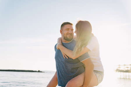 joyful man and woman in love hugging and having fun on sea beach. solar glare