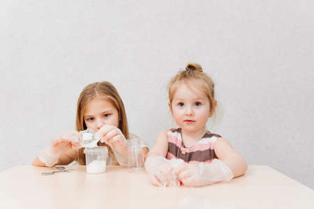 cute little girls in protective gloves conduct an experiments at homeの写真素材