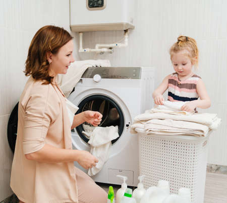 mom and daughter fold laundry after washing in the washing machine.の写真素材