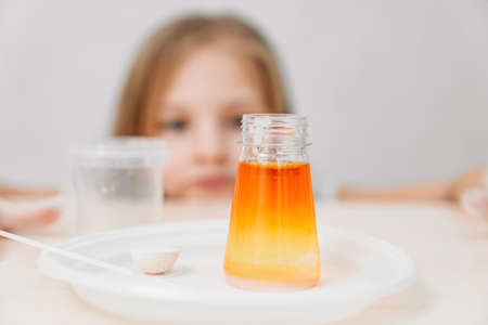 a cute little girl conduct an experiments at home. flask with colored liquidの写真素材
