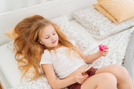 A teenage girl listens to music on her phone with headphones.の写真素材