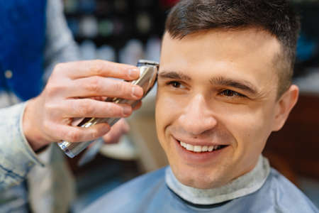 hairdresser makes a haircut of nape for a man with a hair clipper in barbershop