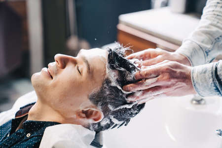 a brunet man washes hair with a hairdresser in a barbershop.の写真素材