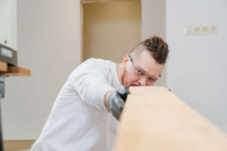 carpenter in protective gloves and glasses with woodの写真素材