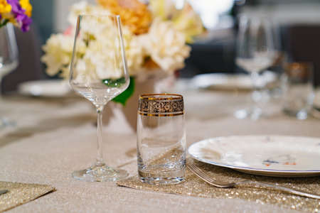 wine glass and beverage glasson served dining table with utensils and flowersの写真素材