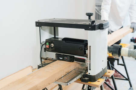 carpenter in protective gloves for working with wood on the planing machineの写真素材