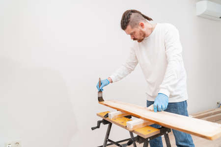 the carpenter covers the wood with oil with a brush.の写真素材