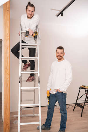 carpenters on stepladder screw with screwdriver wooden lamellae.の写真素材