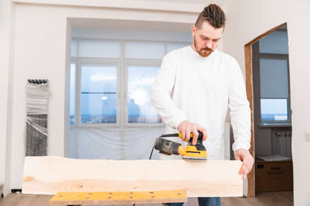 carpenter working on wood grinding machine. grinds and polishes wood.の写真素材