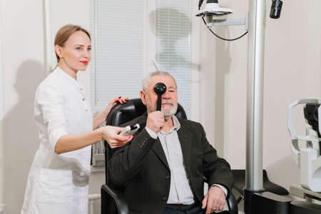 ophthalmologist diagnoses elderly mans vision on a sign projector.