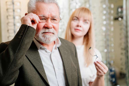 an elderly man with an ophthalmologist chooses glasses in the optics salon.の写真素材