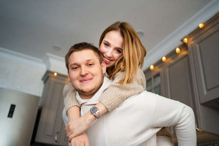 a happy and loving couple fooling around and hugging at home in the kitchen