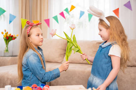little girls with a red headband and rabbit ears hold pink tulip flower in handsの写真素材
