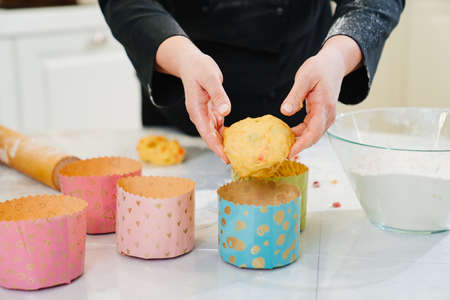 a woman cook lays out dough in paper molds for baking Easter cakes.
