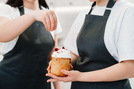 a women decorate icing, dried berries and flowers easter cakes.