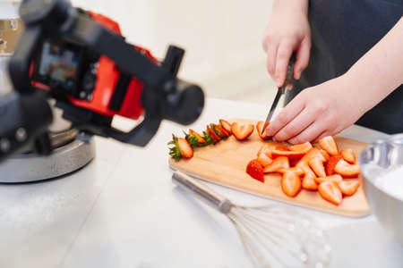 camera takes a video for a cooks or pastry chef in kitchen. cutting strawberriesの写真素材