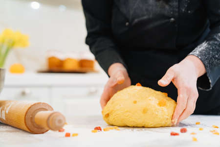 womens hands knead dough with candied fruits for easter cakesの写真素材