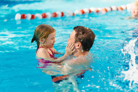 dad and daughter cuddle and swim in the pool. swimming training.の写真素材