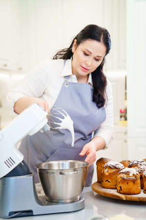 a woman cook prepares icing, fondant or marshmallow to decorate easter cakes.の写真素材