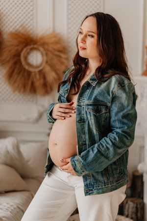 a beautiful pregnant woman in a denim jacket with a naked tummy