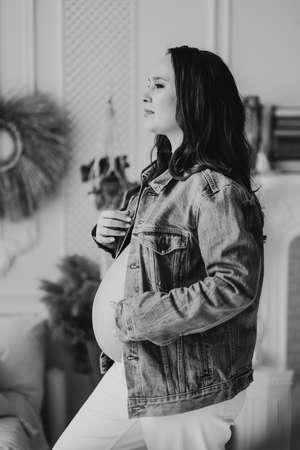 black and white. a beautiful pregnant woman in a denim jacket with a naked tummyの写真素材