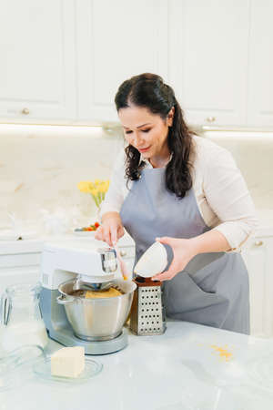 a woman cook adds citrus zest to the bowl of a mixer to make pastries or cream.