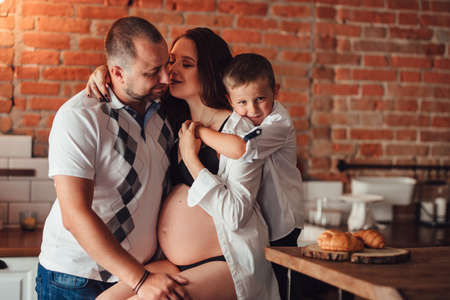 a happy and beautiful family waiting for a child hugging in the kitchenの写真素材