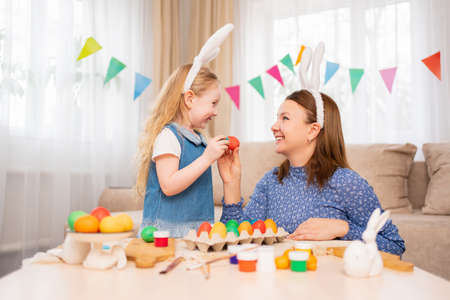 mother and sweet daughter play with Easter eggs in game of who will break.