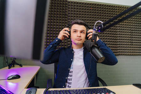 serious radio host broadcasts live reads news on computer screen.の写真素材