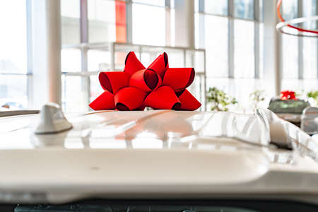 a red gift bow on the roof of a new car in the car dealership.の写真素材