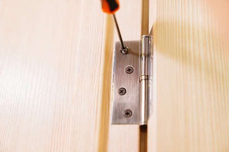 a repairman repairs the door. installation and adjustment of fastenersの写真素材